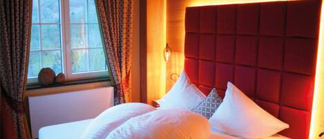 A bedroom with a large bed, a window with curtains, and a red headboard.