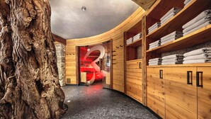 A wooden spa room with a large tree trunk, a sauna, and shelves with towels. - Hotel-Restaurant Rebstock (Durbach)