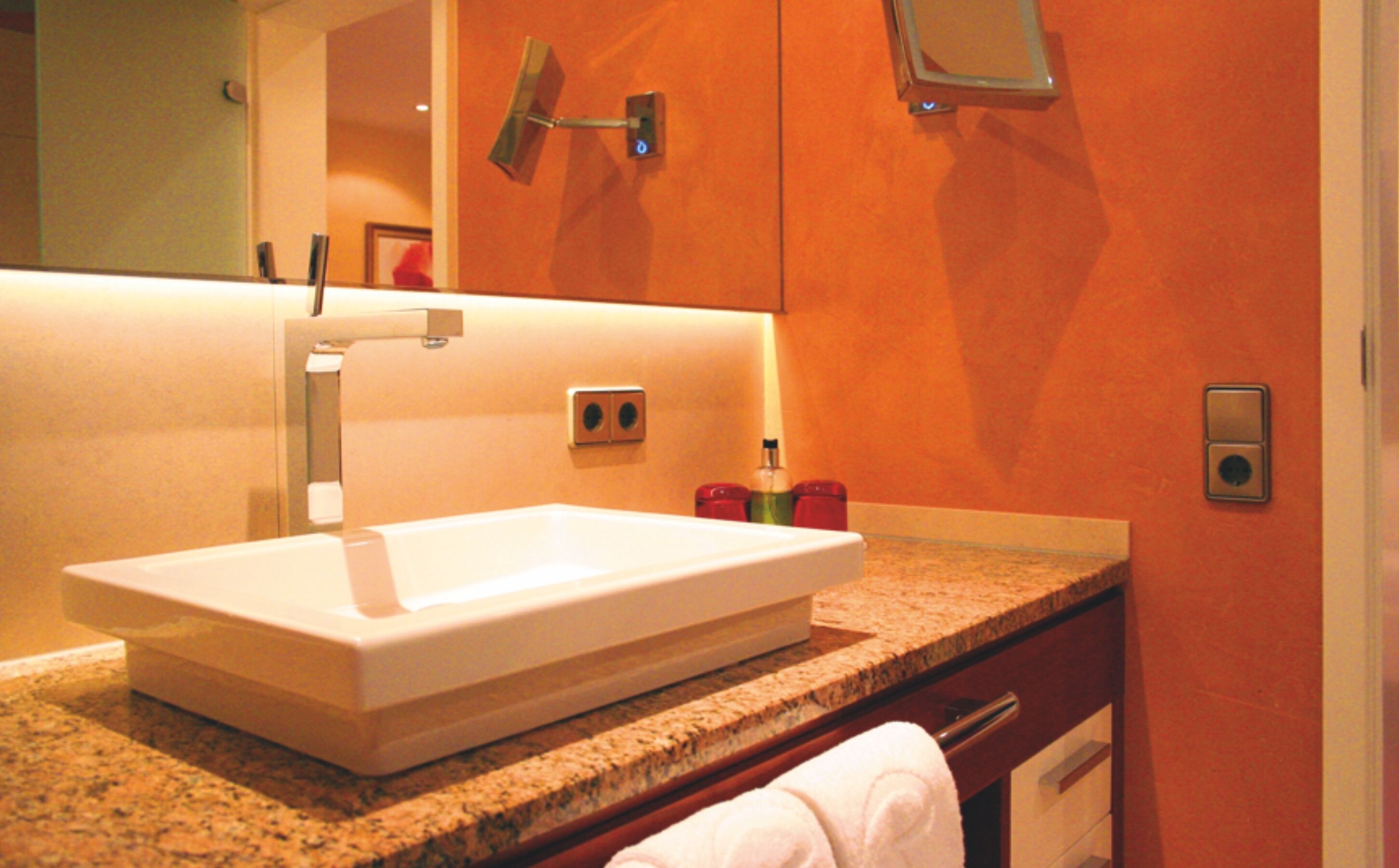 A bathroom with a white sink, granite countertop, and a mirror above it.