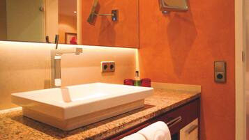 A bathroom with a white sink, granite countertop, and a mirror above it.