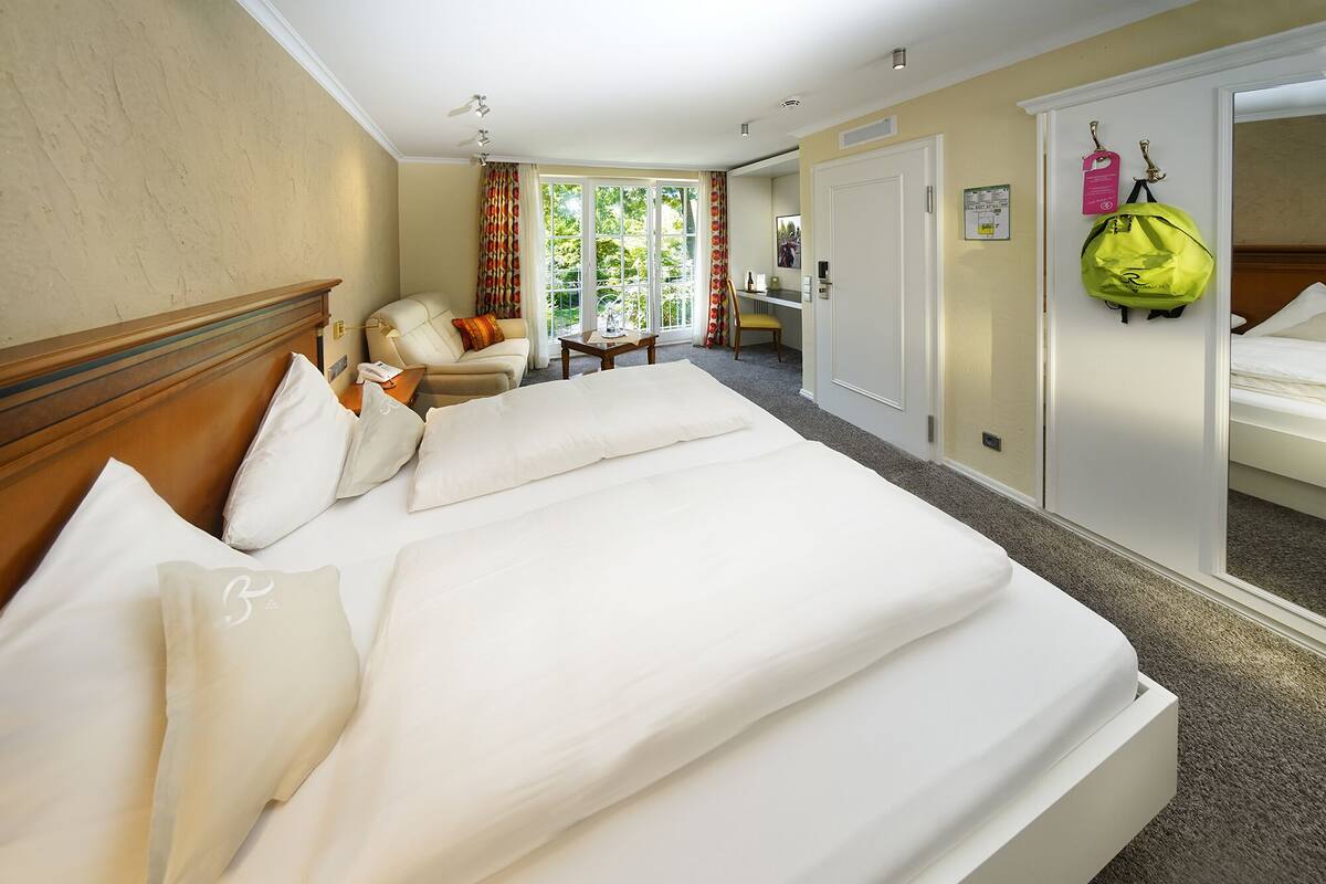 Ein Hotelzimmer mit einem großen Bett, einem Schreibtisch, einem Stuhl und einem fenster mit Vorhängen.