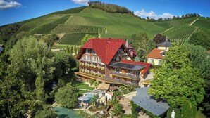 A large, two-story chalet with a red roof, surrounded by lush greenery and vineyards. - Hotel-Restaurant Rebstock (Durbach)