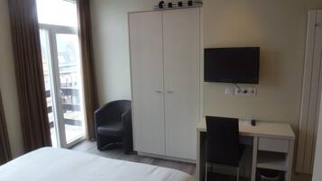 Une chambre d’hôtel comprenant un lit, un bureau avec une chaise, une télévision et une armoire.