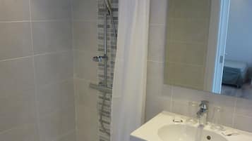 Ein modernes Badezimmer mit Dusche, Waschbecken und Spiegel.