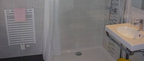 A bathroom with a shower, a sink, and a toilet.