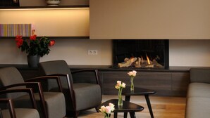 Un salon moderne doté d’une cheminée, de sièges confortables et d’un grand luminaire suspendu.