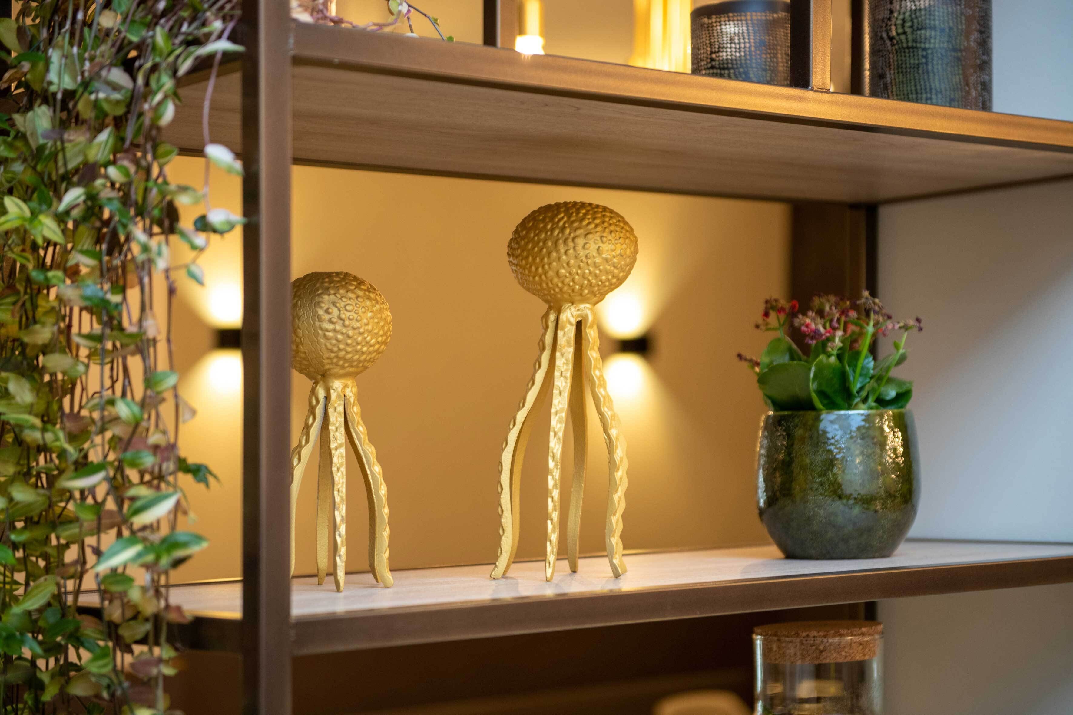 A shelf with decorative golden objects and a green plant.