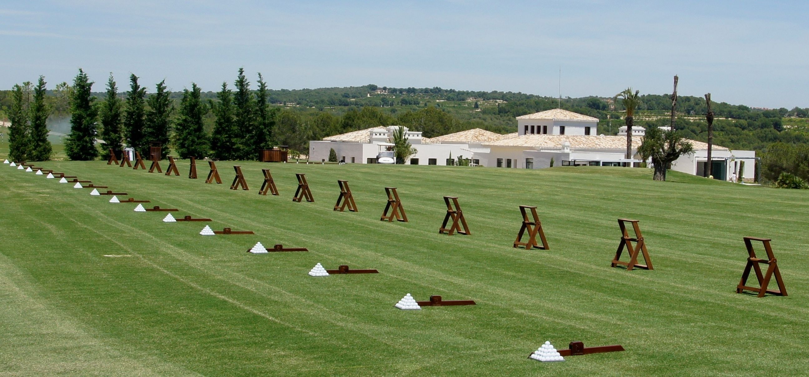 A golf course with a series of wooden tees and white cones arranged in rows.