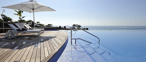 Una piscina al aire libre, sillones reclinables de piscina