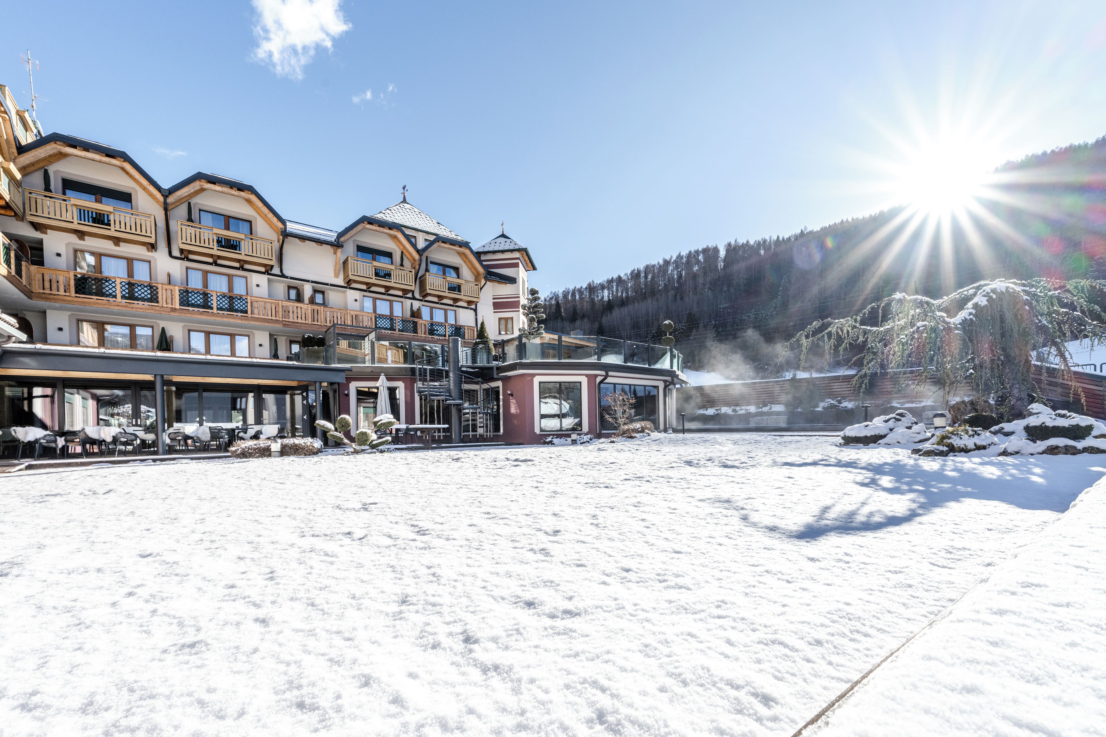 Un hotel con numerosi balconi, una zona relax coperta all'aperto e vista su una montagna innevata.