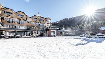 Un hotel con numerosi balconi, una zona relax coperta all'aperto e vista su una montagna innevata.