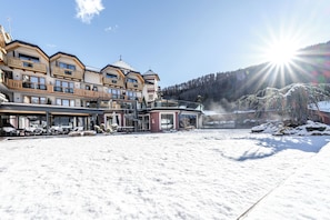Un hotel con varios balcones, una zona de estar al aire libre techada y vistas a una montaña nevada.