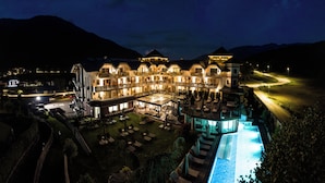 A large hotel with multiple balconies, a swimming pool, and a well-lit outdoor area.