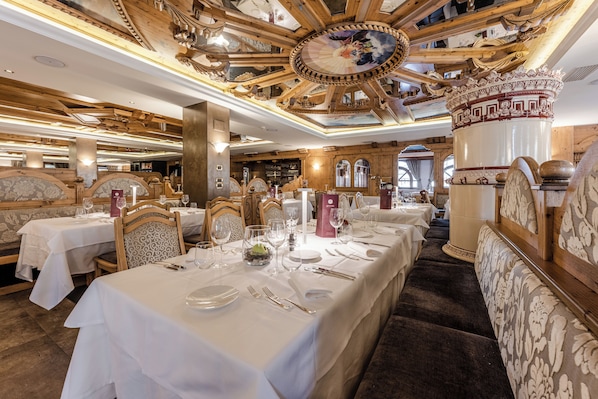 Un restaurante con interiores de madera, manteles blancos y elaboradas decoraciones en el techo.