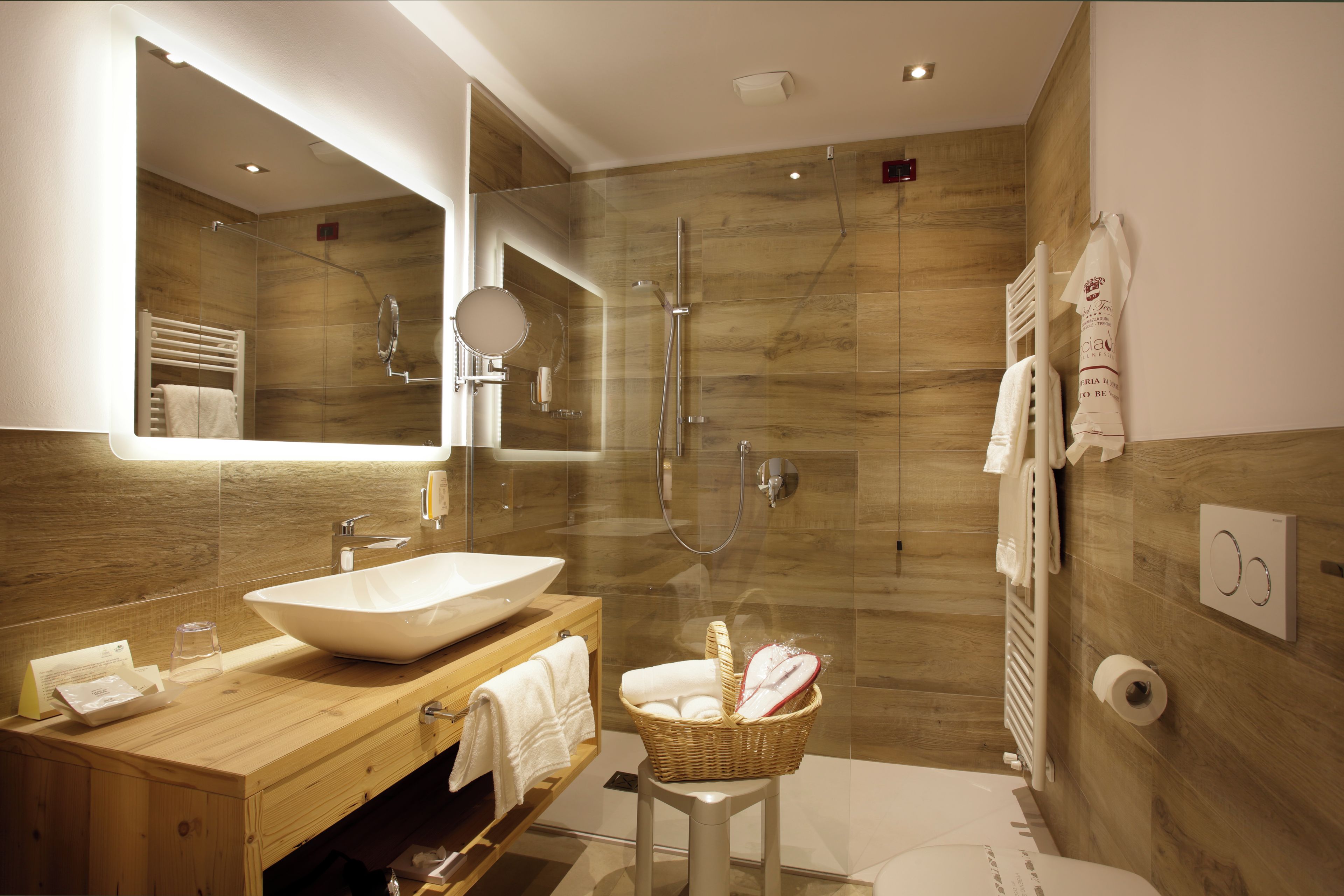 Un bagno moderno con un mobile bagno in legno, uno specchio grande, una vasca freestanding e una doccia con box in vetro.