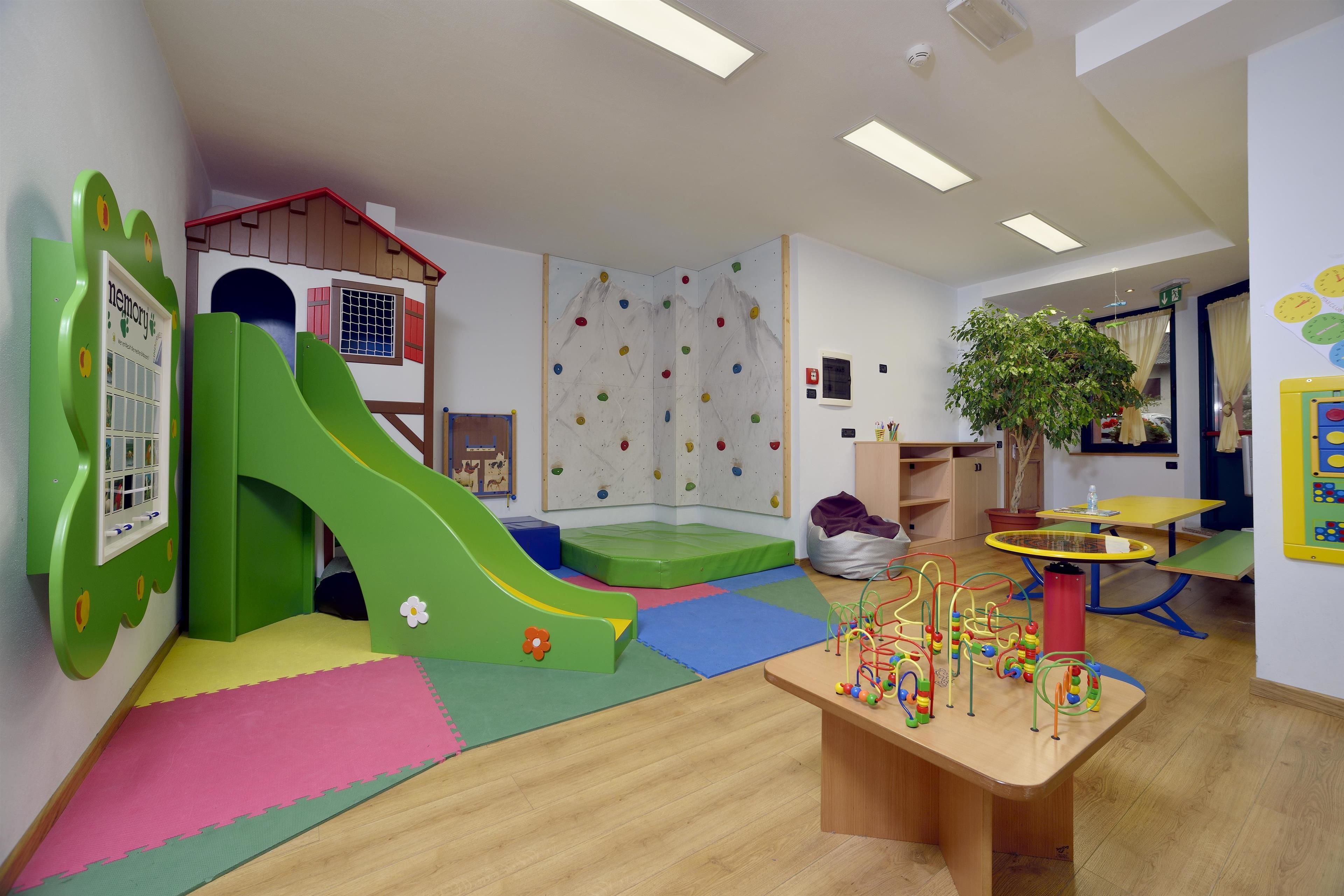 Un'area giochi per bambini con scivolo, parete da arrampicata e tanti giocattoli.