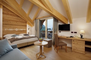 Un dormitorio moderno con techo de madera, una cama con almohadas, una mesita de noche con fruteros, un escritorio con lámpara y un televisor en la pared.