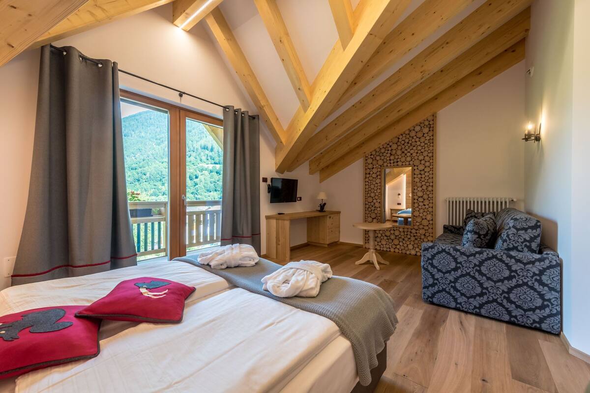 Een slaapkamer met een groot bed, een bureau, een stoel en een televisie.