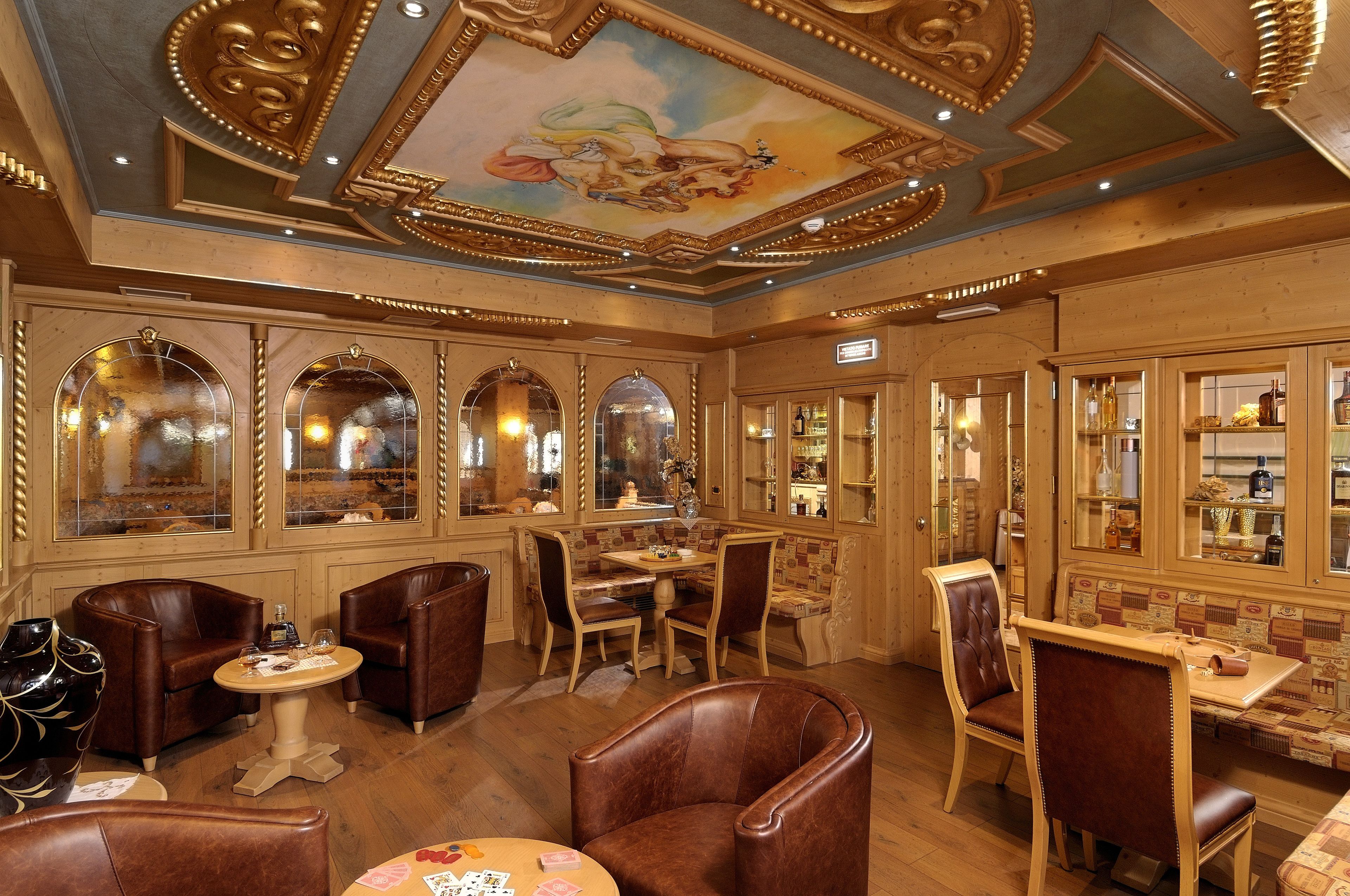 Une chambre luxueuse avec un plafond en bois, des miroirs décoratifs et un coin repas comprenant des fauteuils en cuir et une table.