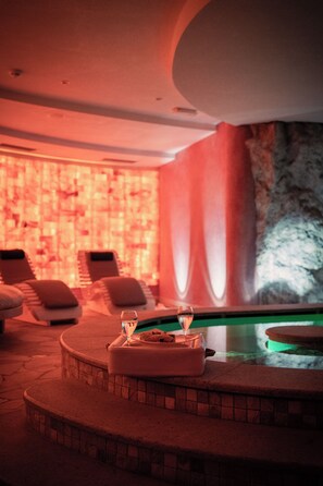 Un área de spa con piscina, sillas de descanso y camilla de masaje.