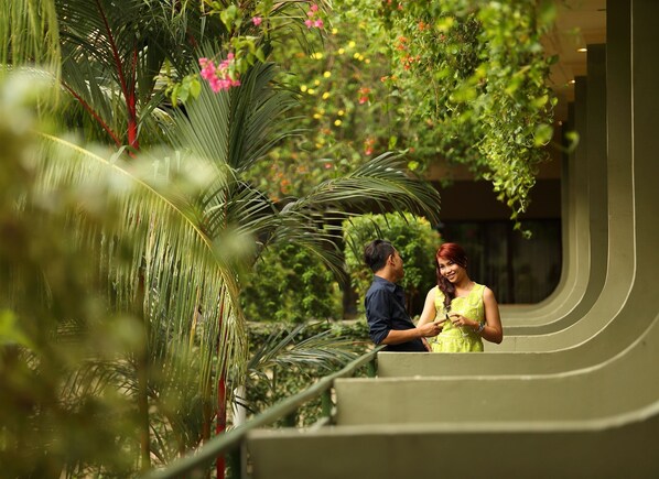 A couple standing on a curved staircase surrounded by lush greenery and plants.