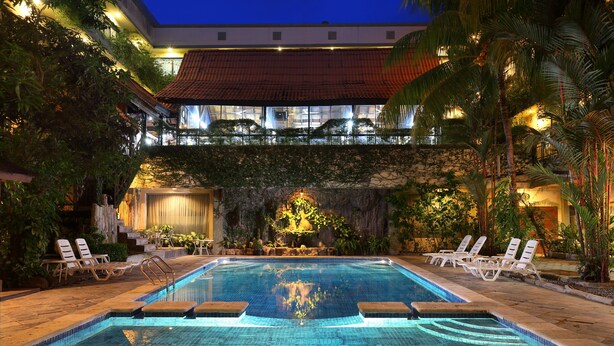 A swimming pool with steps leading into it, surrounded by lounge chairs and palm trees. - Goodway Hotel Batam (Batam)