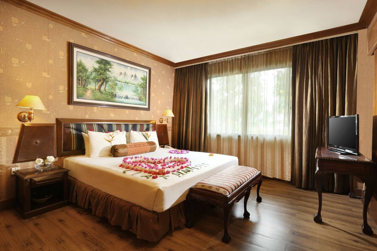 Habitación de hotel con una cama grande, televisión, escritorio y un cuadro en la pared.