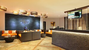 A reception area with a dark wall, a 'Spa' sign, wicker furniture, and a reception desk. - Goodway Hotel Batam (Batam)
