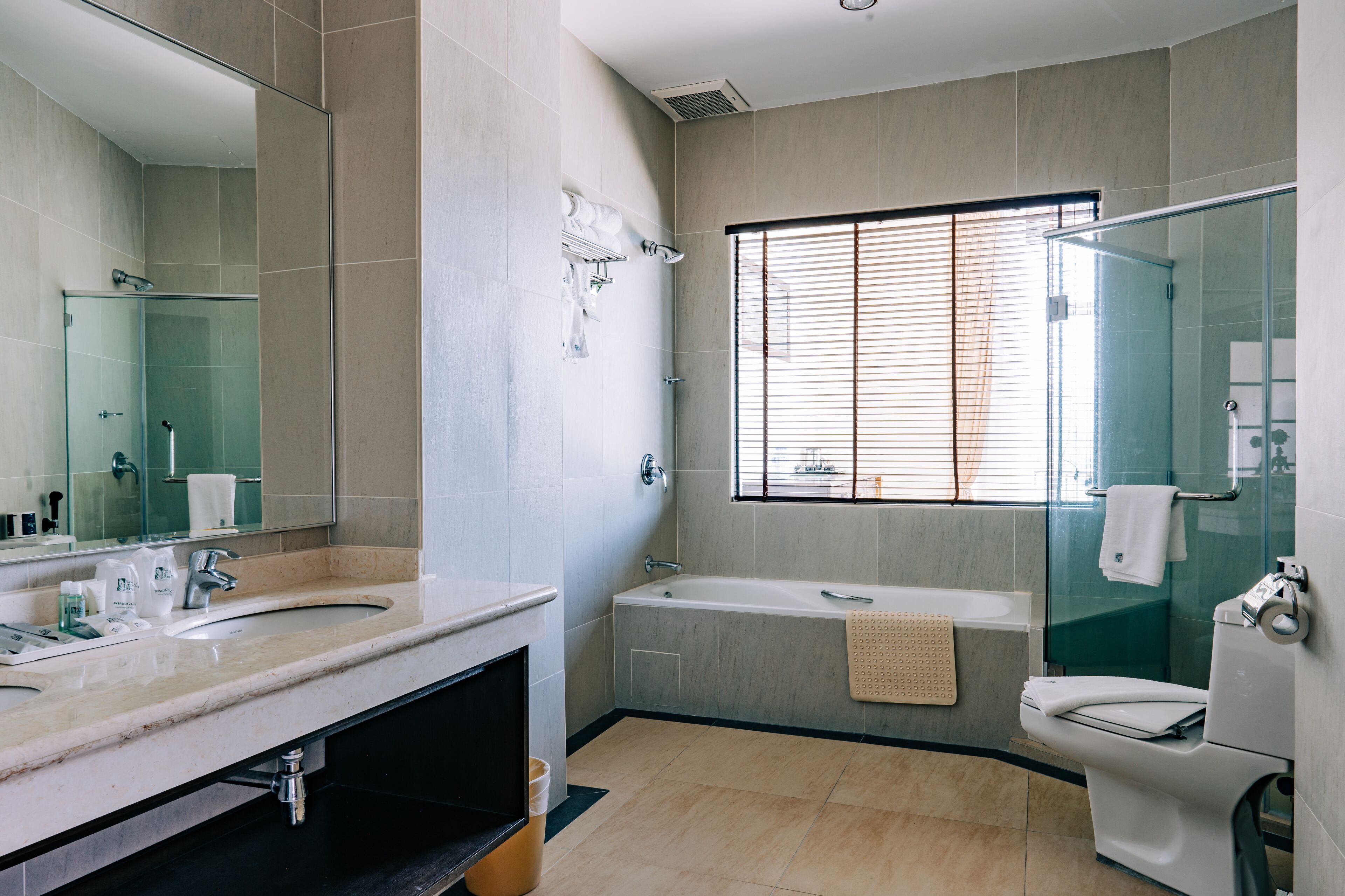 Een moderne badkamer met een wastafel met dubbele wastafel, een badkuip en een douche met glazen wand.