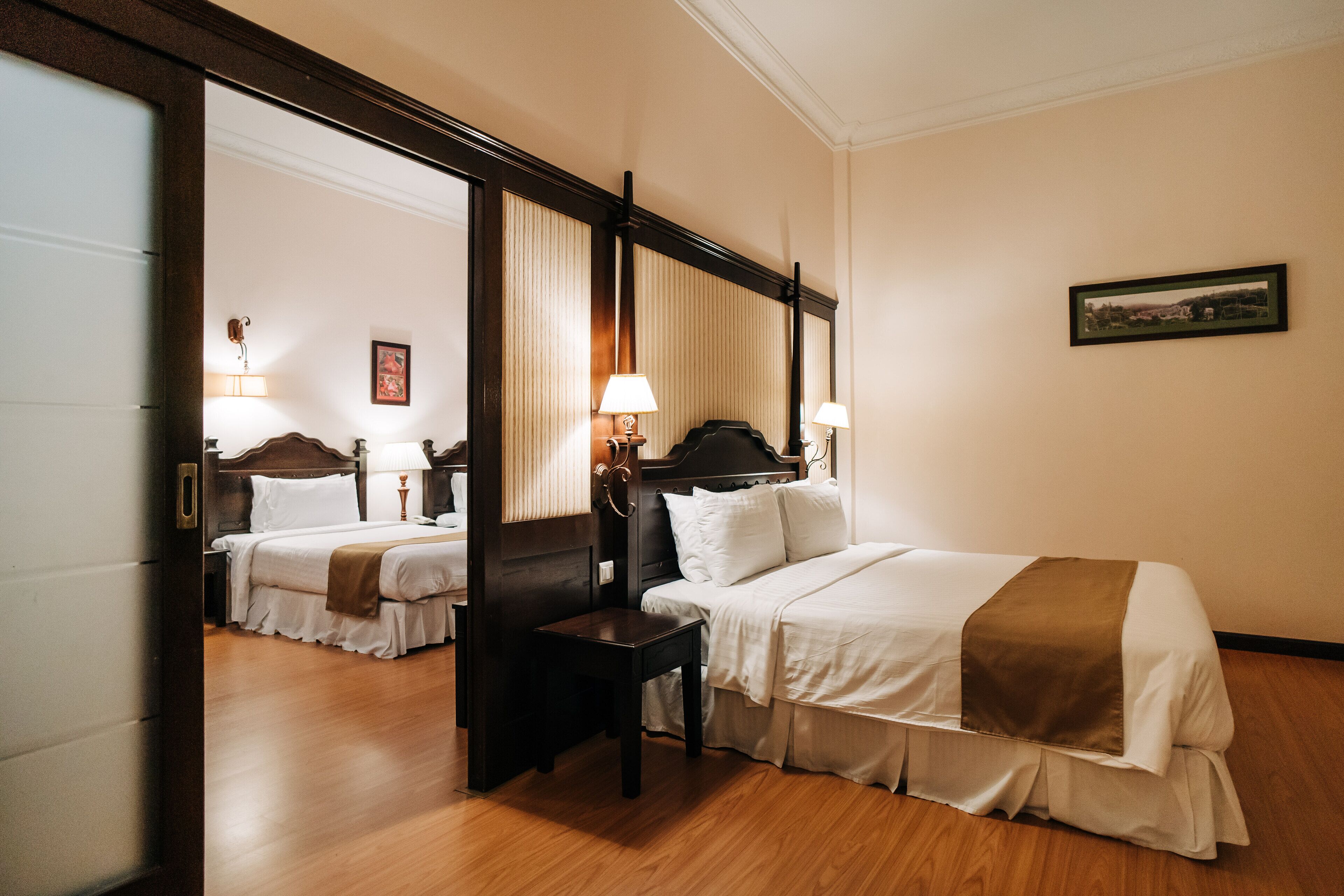A hotel room with a large bed, a bedside table, a mirror, and a picture on the wall.