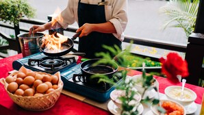 A chef cooking on an outdoor grill with a basket of eggs and various food items on the table. - Hotel De'La Ferns, Cameron Highlands (Tanah Rata)