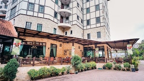 A hotel with a stone facade, outdoor seating area, and a covered patio. - Hotel De'La Ferns, Cameron Highlands (Tanah Rata)