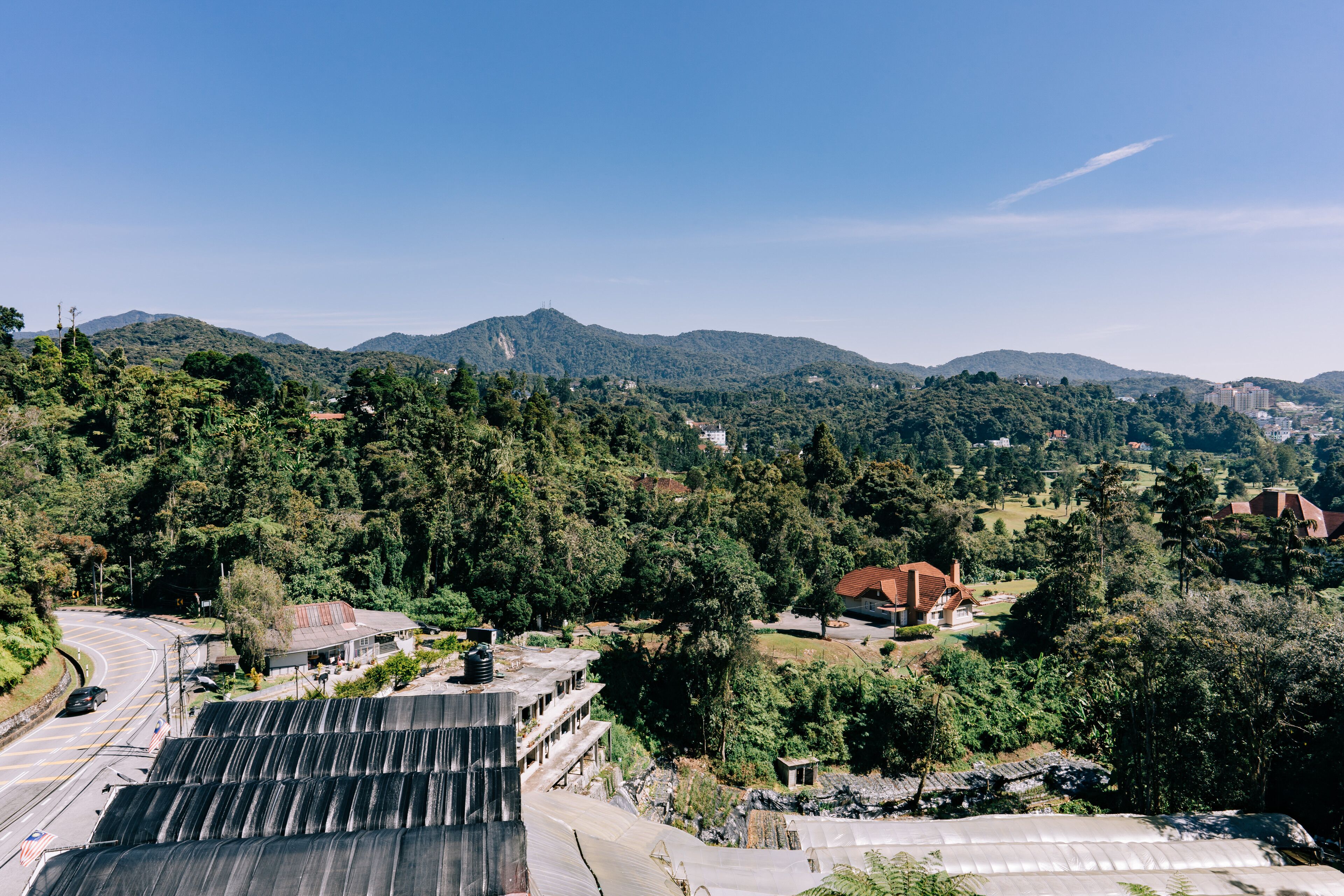 Vista de un paisaje montañoso con una carretera, edificios y vegetación.