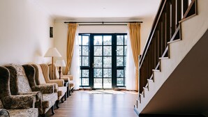 A spacious room with a wooden floor, a set of four patterned armchairs, a lamp, and a large window with curtains. - Hotel De'La Ferns, Cameron Highlands (Tanah Rata)