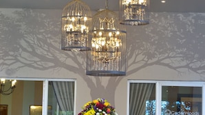 Een hal met een glazen tafel, een bloemstuk en drie hanglampen.
