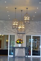Un hall con una mesa de vidrio, un centro de mesa floral y tres lámparas colgantes.