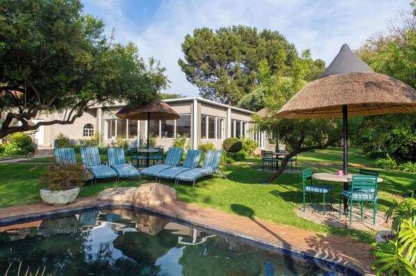 Alberca al aire libre, sombrillas en la alberca y camastros 