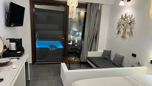 Quarto de hotel moderno com cama, área de estar e vista para uma piscina.