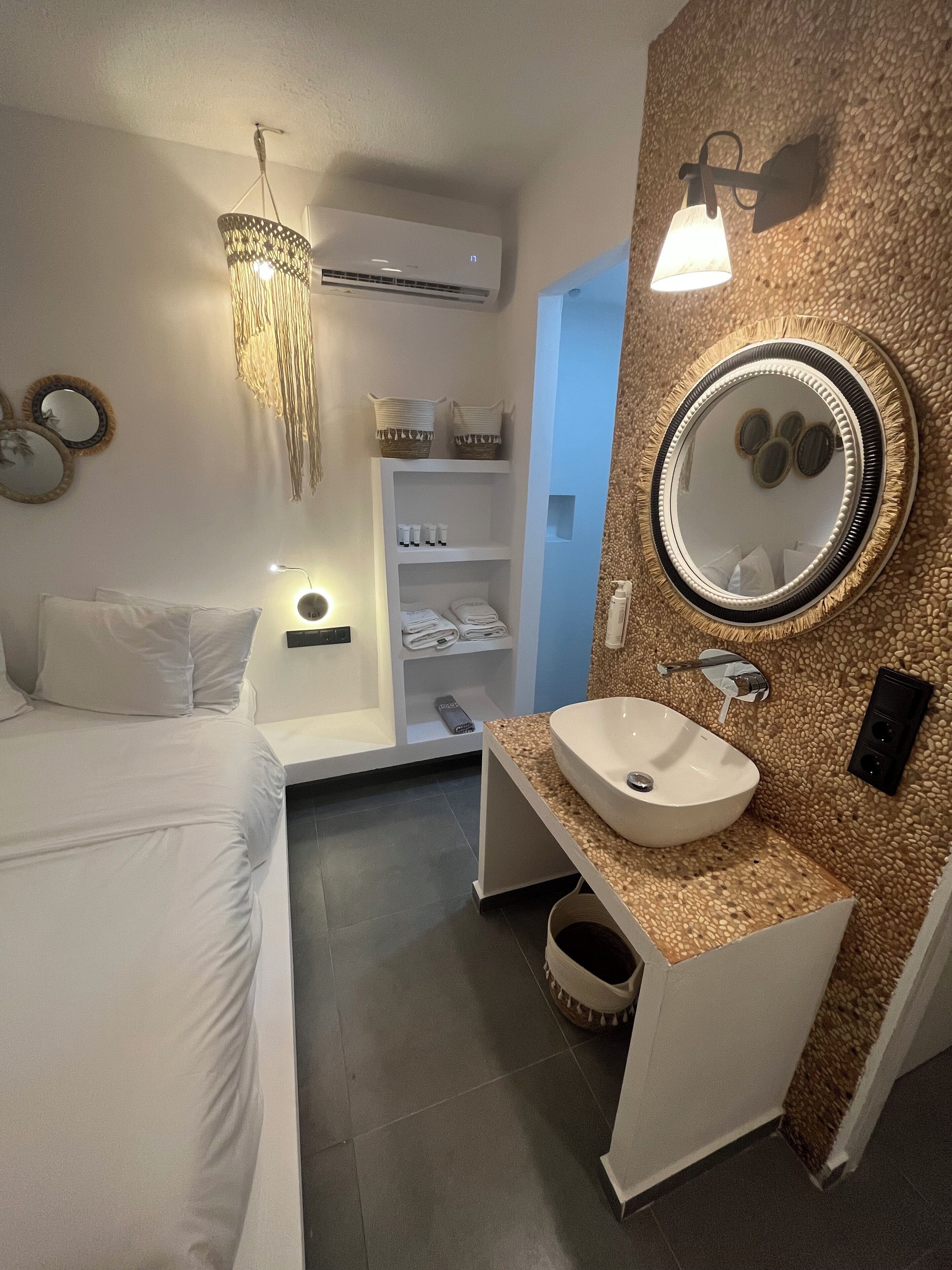 A modern bedroom with a bed, bedside table, and a wall-mounted air conditioner.