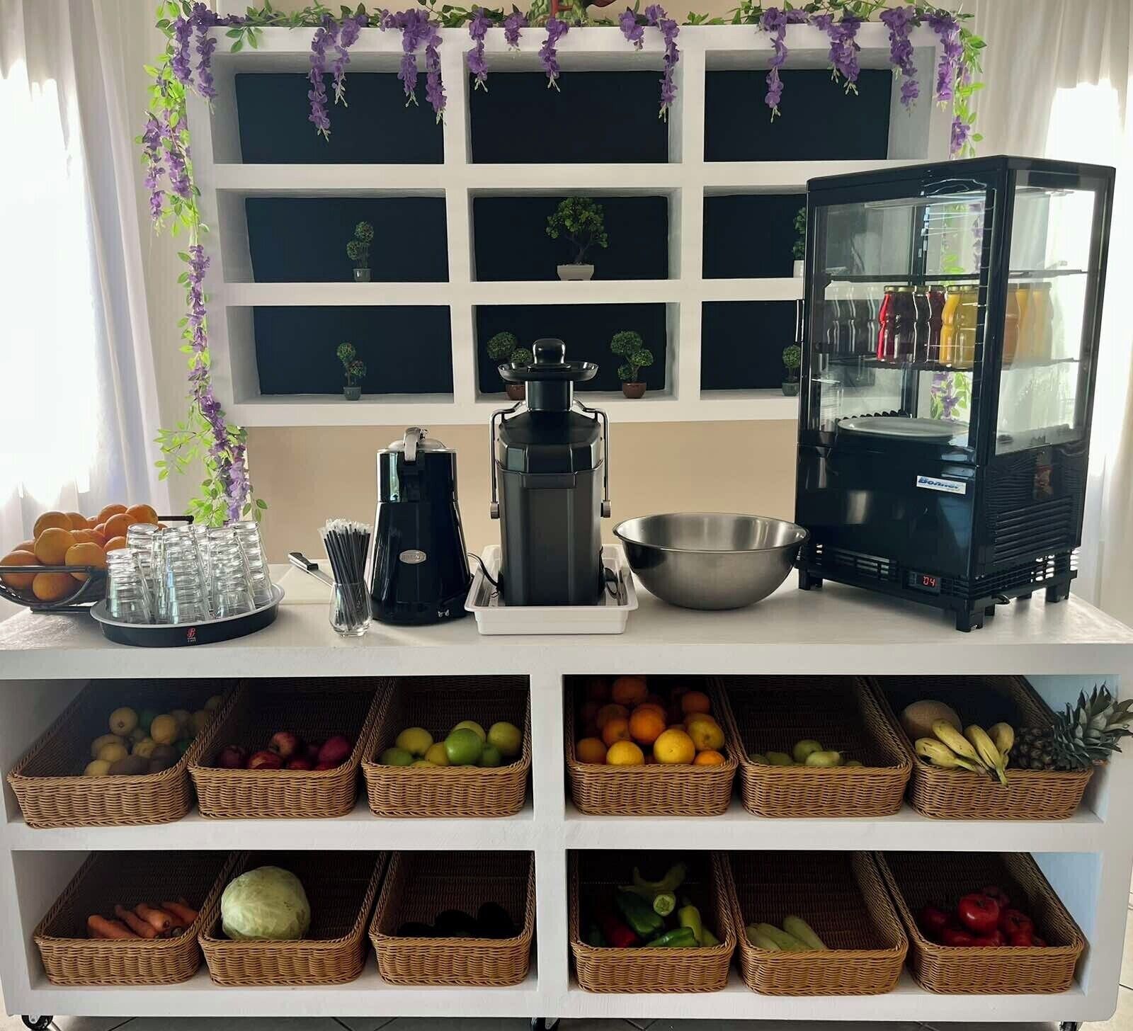 A kitchen area with a coffee maker, a blender, a fruit basket, and a refrigerator.