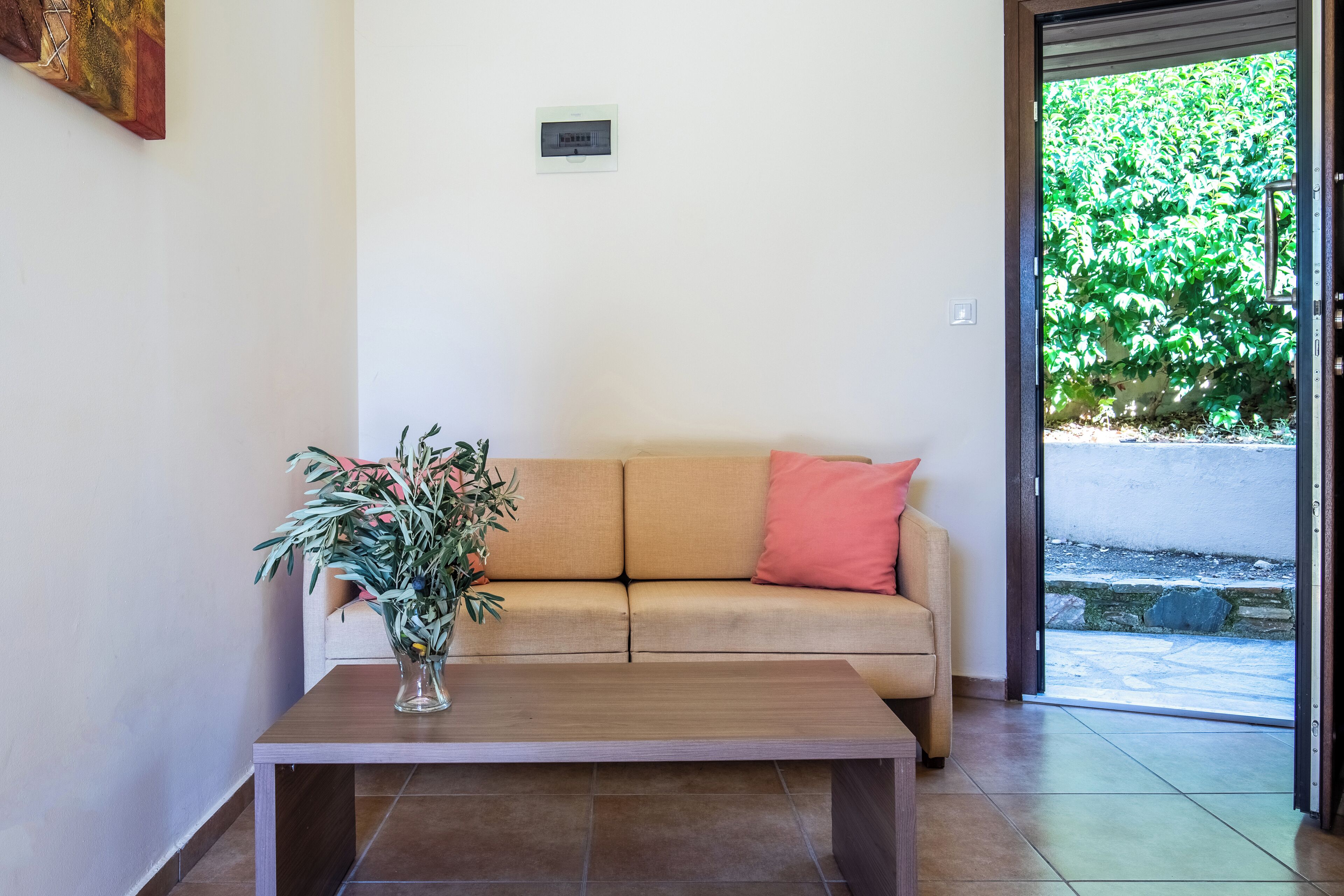 A room with a beige sofa, a wooden coffee table, and a potted plant.