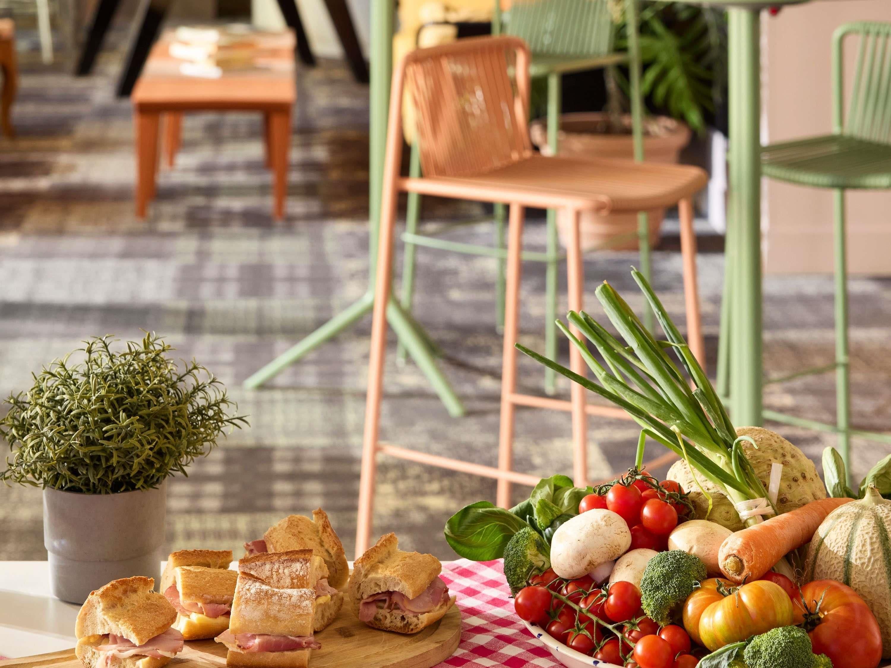 Une table sur laquelle on trouve une variété d’aliments, notamment des sandwichs, des légumes et une plante en pot.