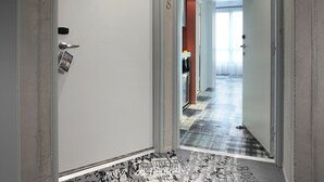 A hallway with a patterned floor, doors numbered 216 and 218, and a bright light at the end. - Mama Shelter Marseille (Marseille)