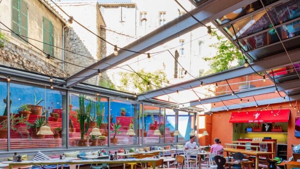 Un espacio al aire libre para comer con mesas, sillas y diversas plantas.