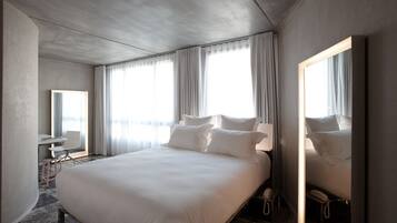 Una camera d'albergo con un letto grande, una scrivania con una sedia, uno specchio e un telefono.