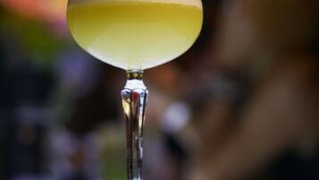 A cocktail glass with a frothy top, placed on a reflective surface.