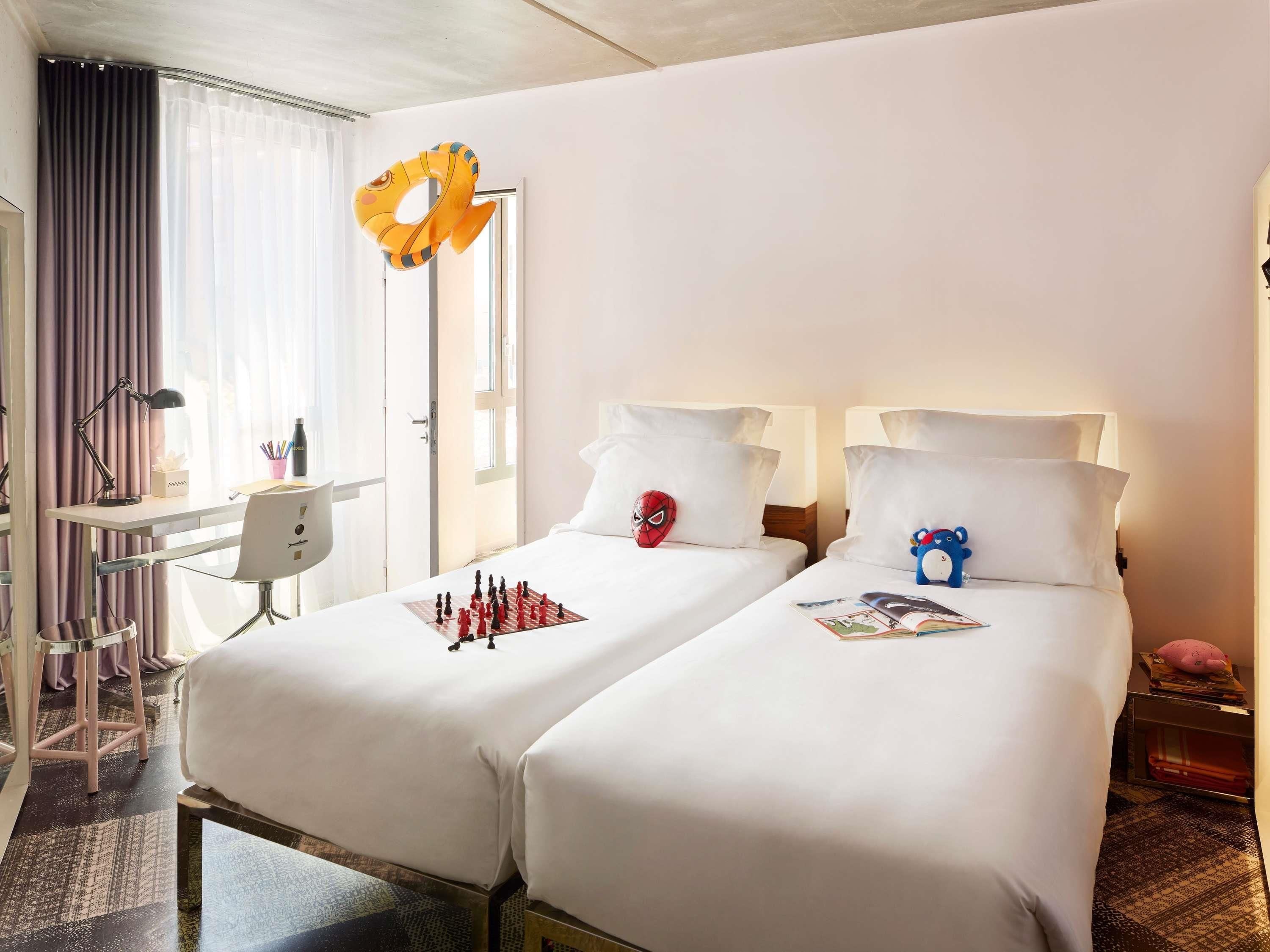 Une chambre d’hôtel avec deux lits, un bureau et une chaise.