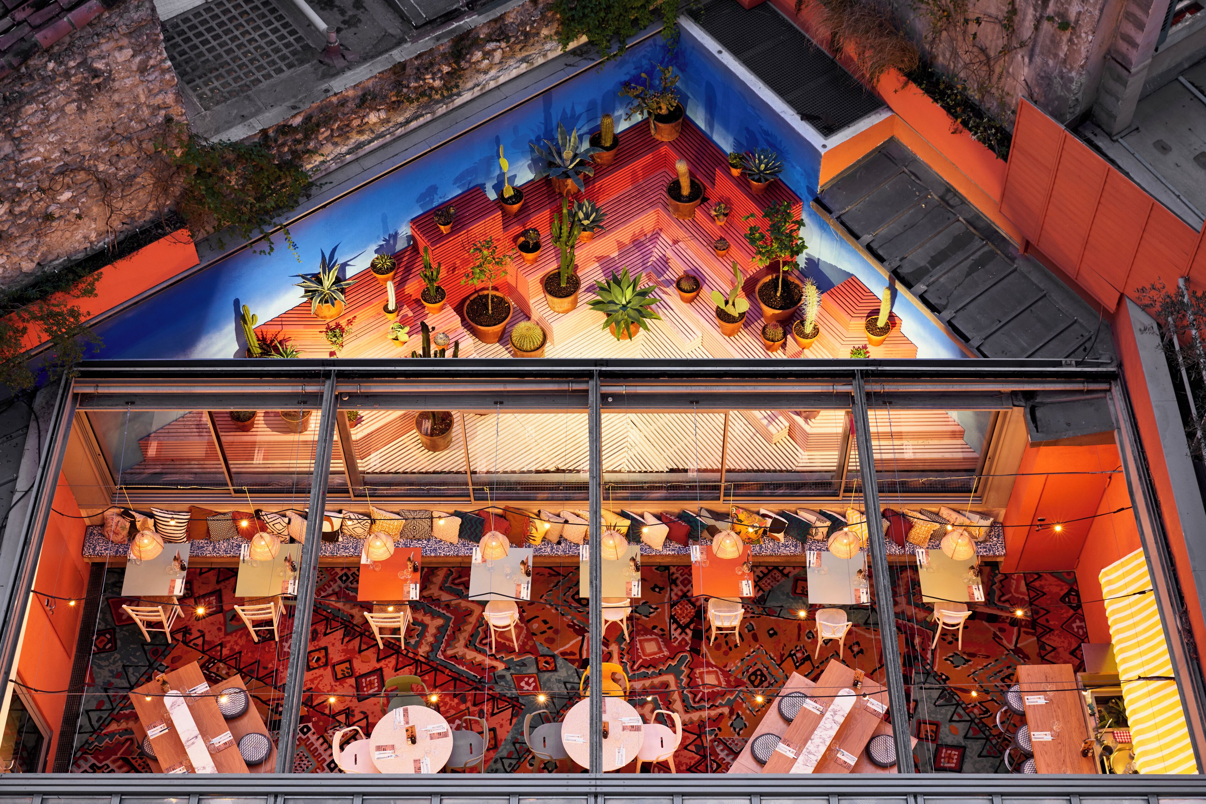 A restaurant with a colorful mural, potted plants, and a variety of seating arrangements.