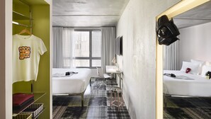 A hotel room with two beds, a desk, a chair, a wardrobe, and a mirror. - Mama Shelter Marseille (Marseille)