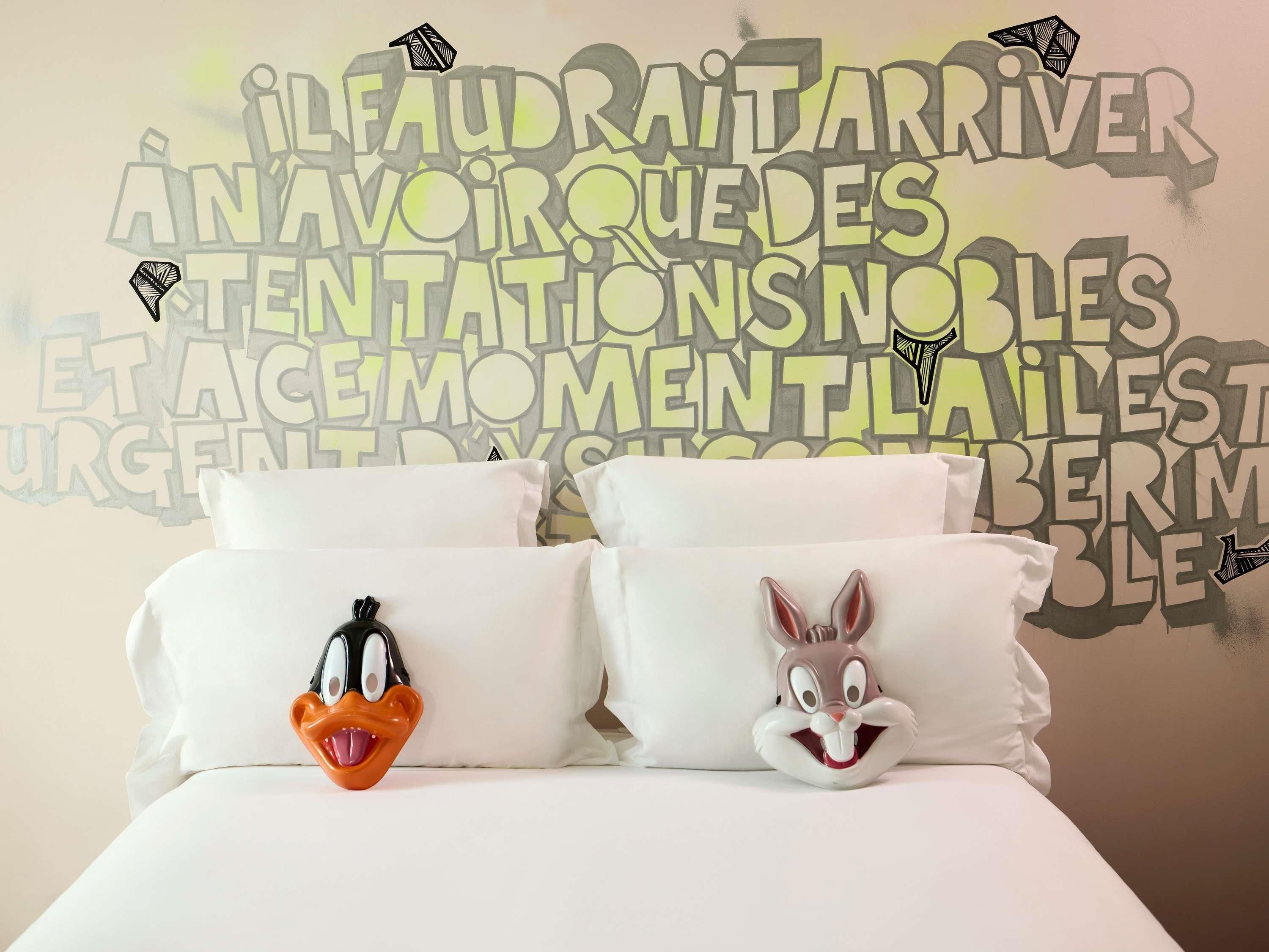 Uma cama com dois travesseiros, um com um pato de desenho animado e outro com um coelho.